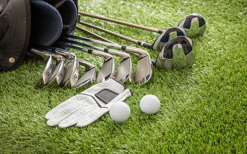 Golf bag with clubs, balls, and glove on grass