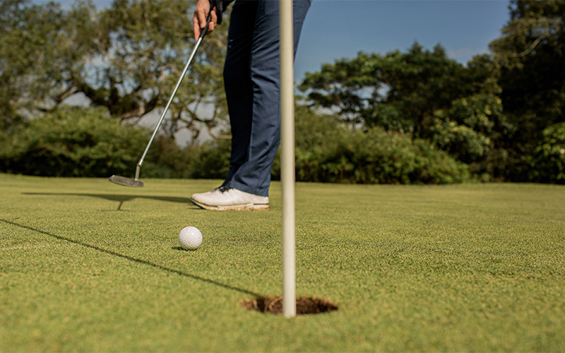 Golfer preparing putt on green.